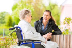 elder in a wheelchair talking to her caregiver